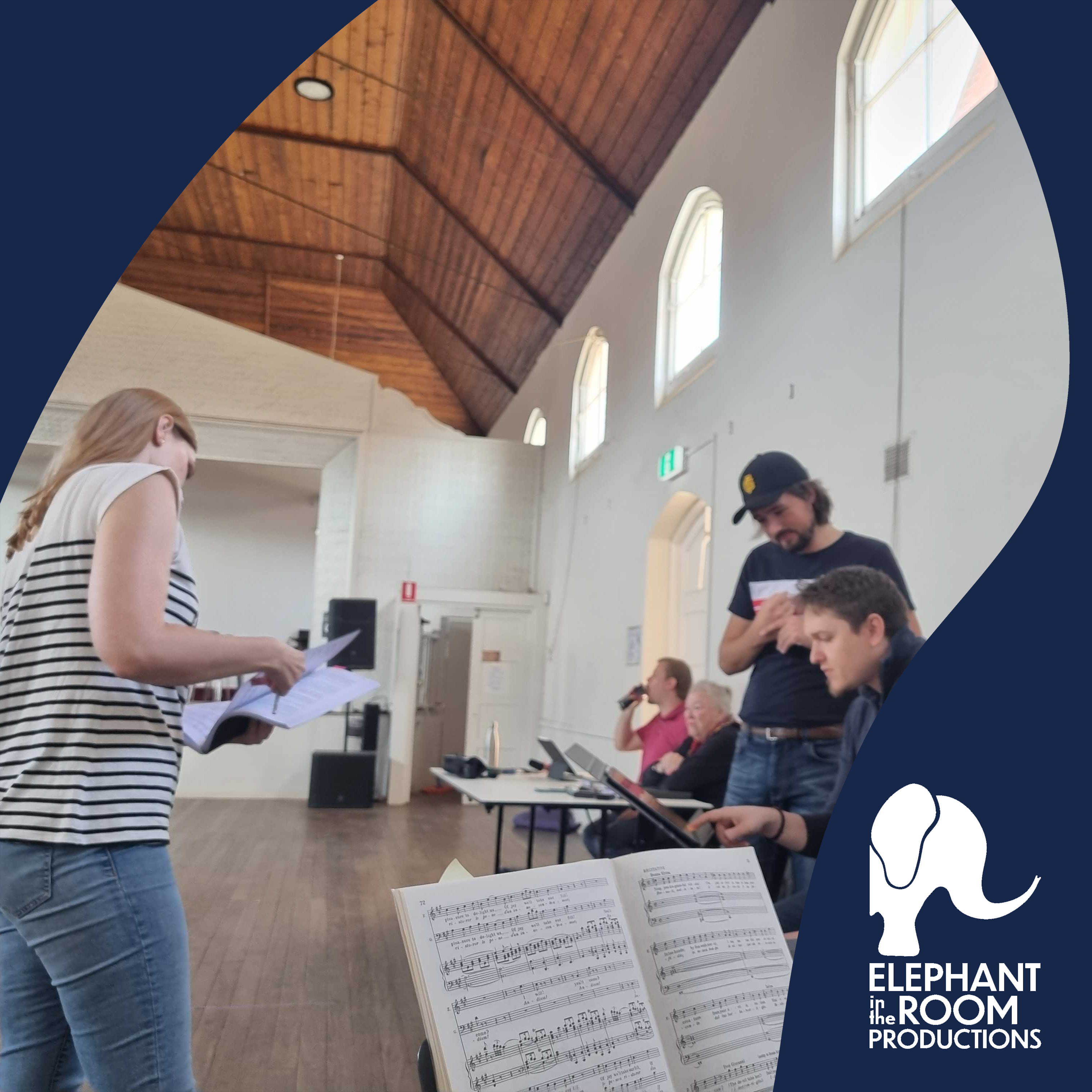 Conductor, Sean Renaud (right) talks with Blake Ascione (standing, right) and Lexie (left) at a rehearsal